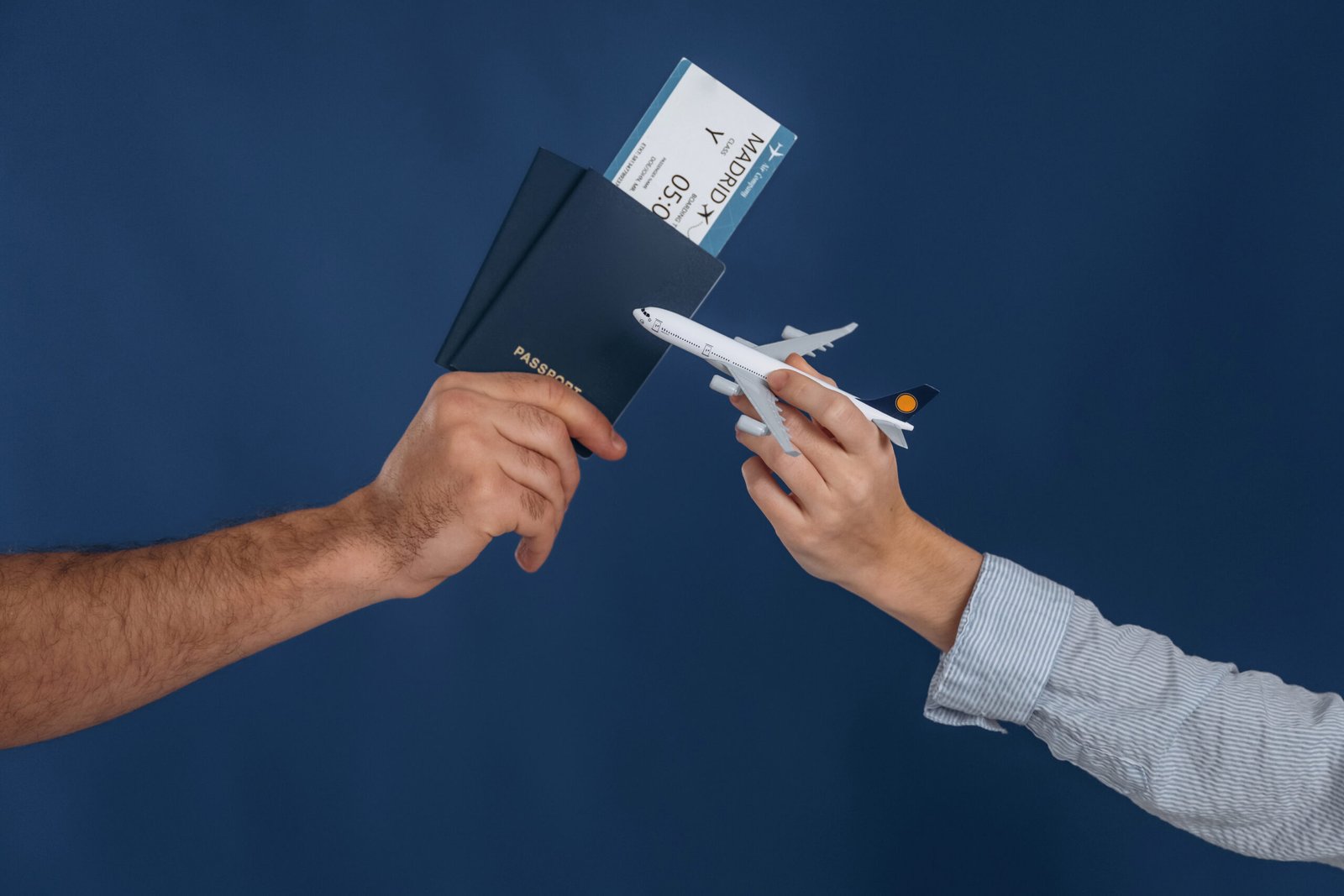 ticket and toy plane. close up view of woman's and man's hands that are ready for vacation